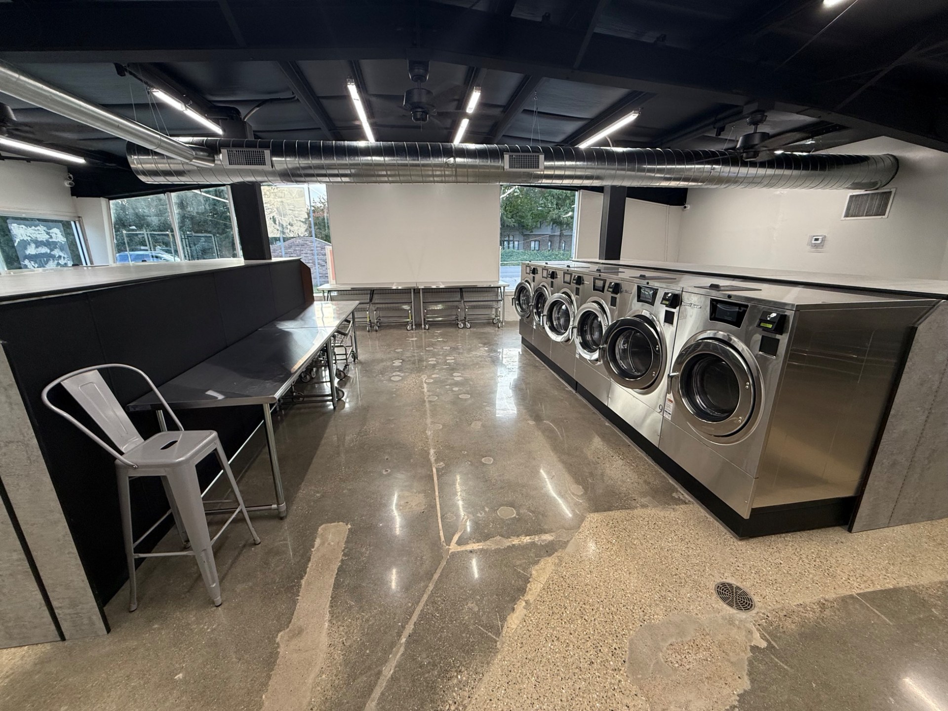 Spacious Champaign Laundry interior with stainless steel washers and folding tables